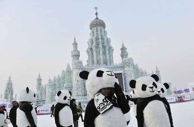 Employees wearing panda costumes stand in front of ice sculptures during the Harbin International Ice and Snow World festival in Harbin